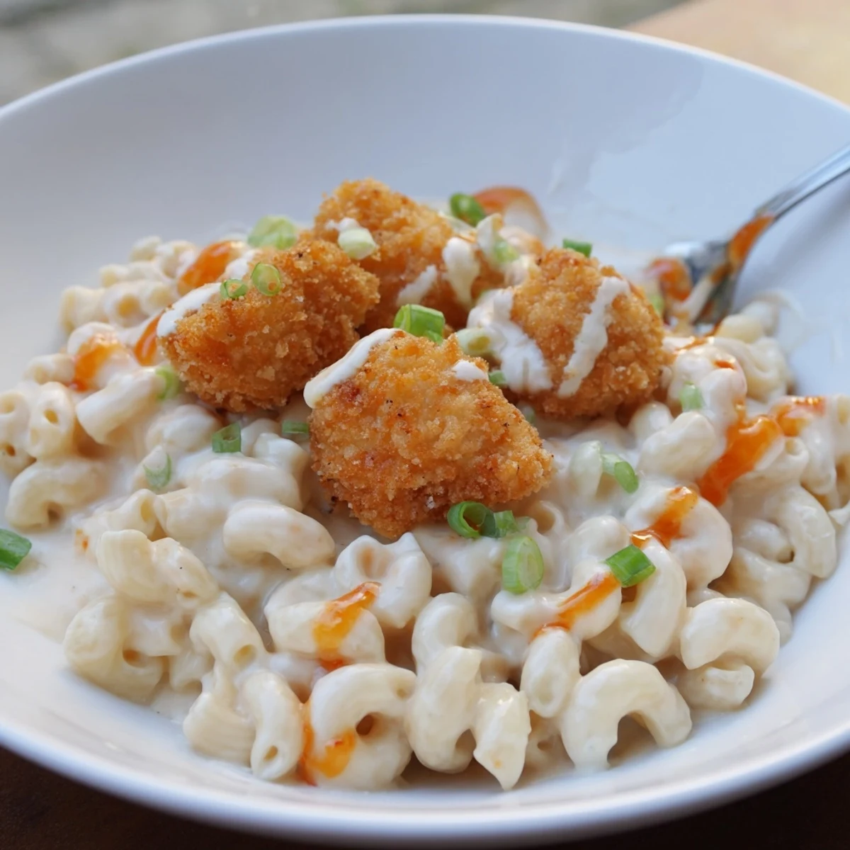 Crispy chicken bites atop creamy sweet chili chicken mac and cheese dish.  