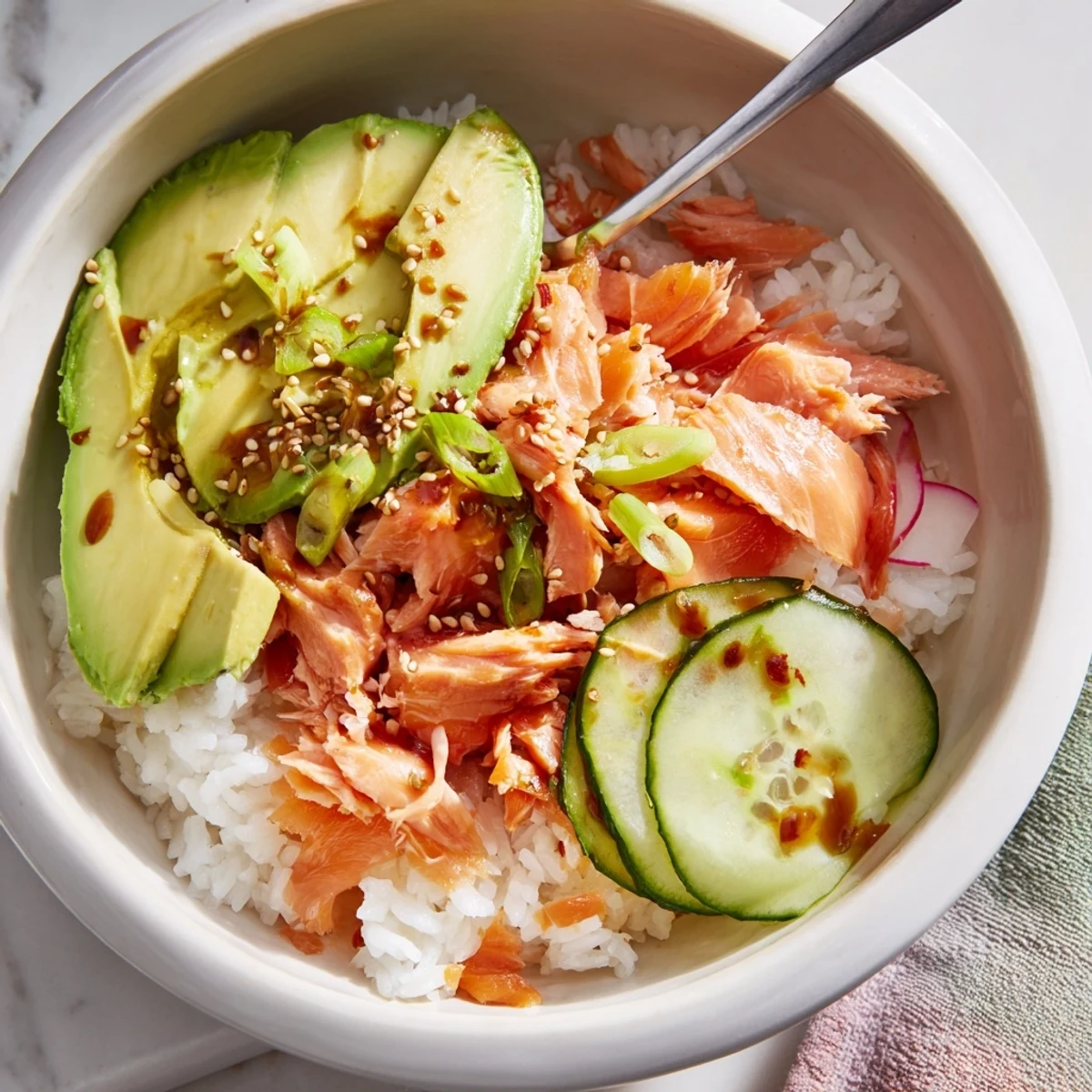 Delicious leftover salmon and rice bowl topped with fresh avocado and cucumber slices.  