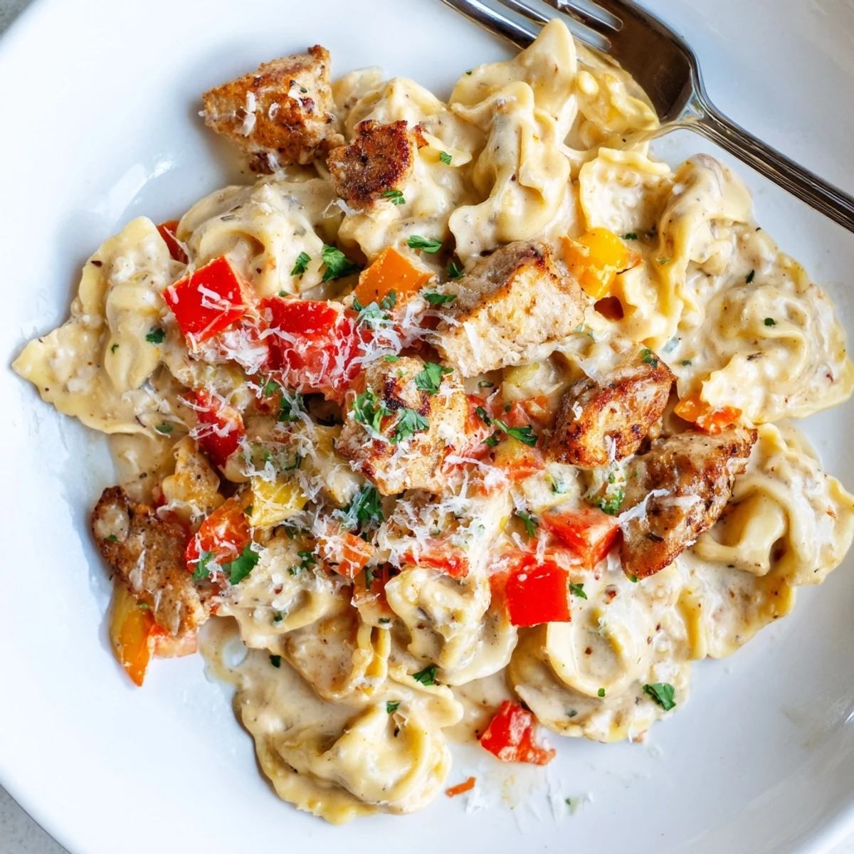 A creamy, spicy Zesty Cajun Garlic Parmesan Chicken Tortellini dish garnished for flavor.  