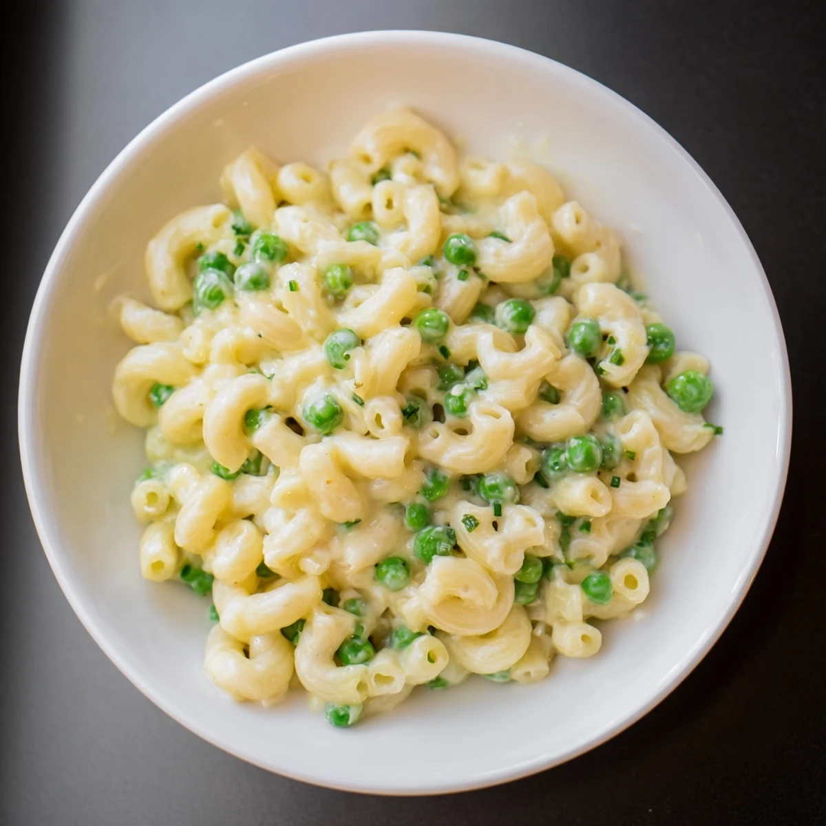 A steaming skillet of creamy Macaroni & Peas, bubbling with flavorful sauce and green peas.