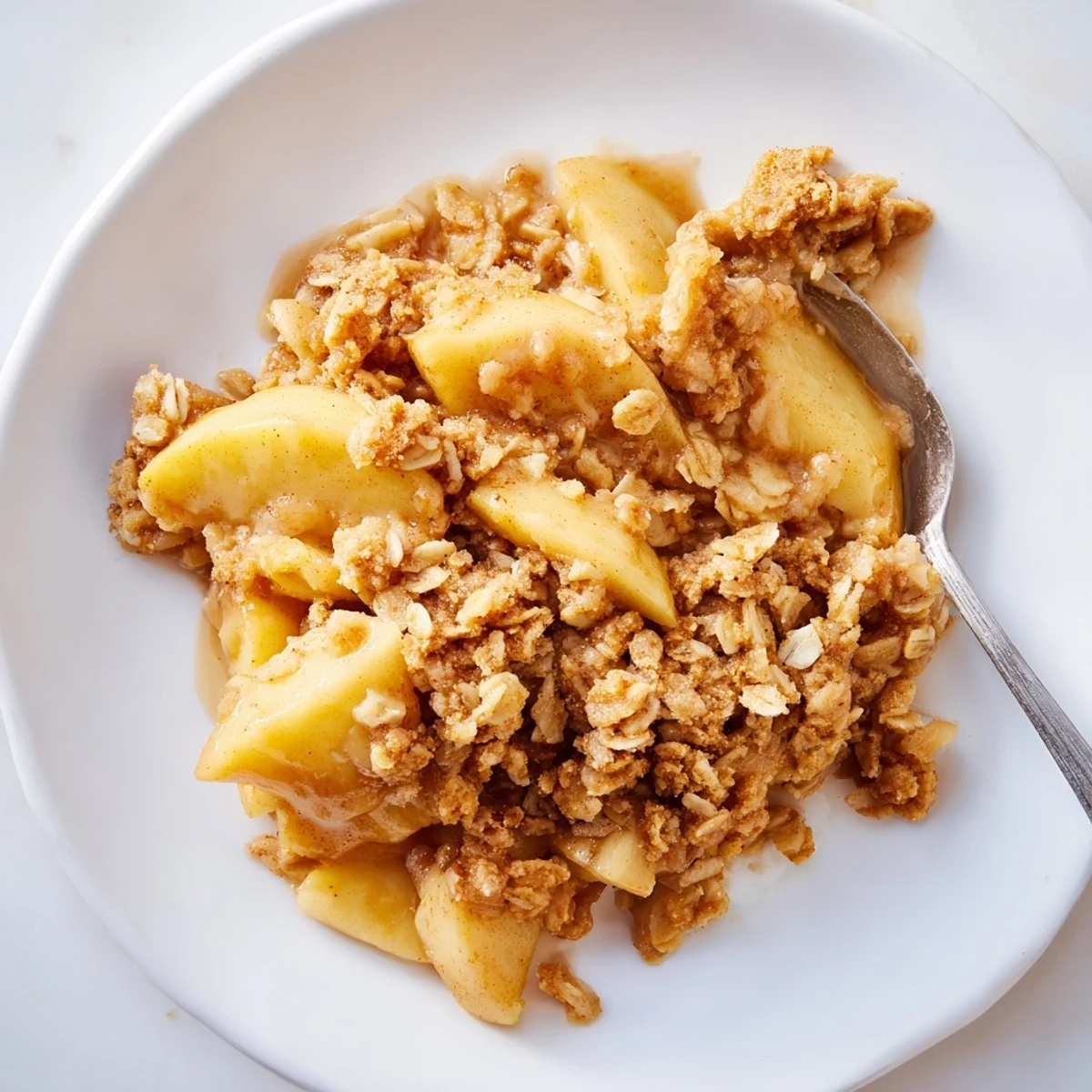 Close-up of baked Best Apple Crisp, showcasing the tender apples under a crispy oat crumble topping.