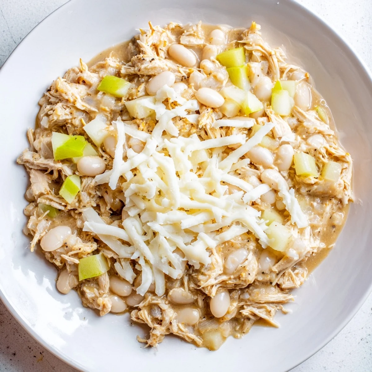Steaming white cheddar apple chicken chili topped with extra cheddar and diced green apples.