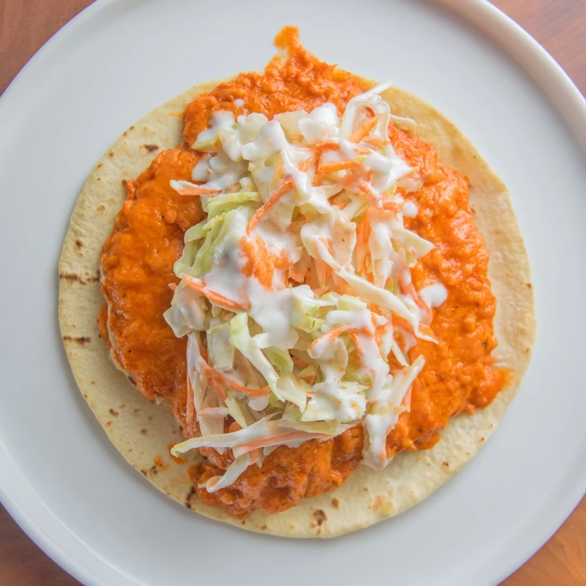 Close-up of a plated Buffalo Chicken Smash Burger Taco, showcasing the textures of the ingredients.