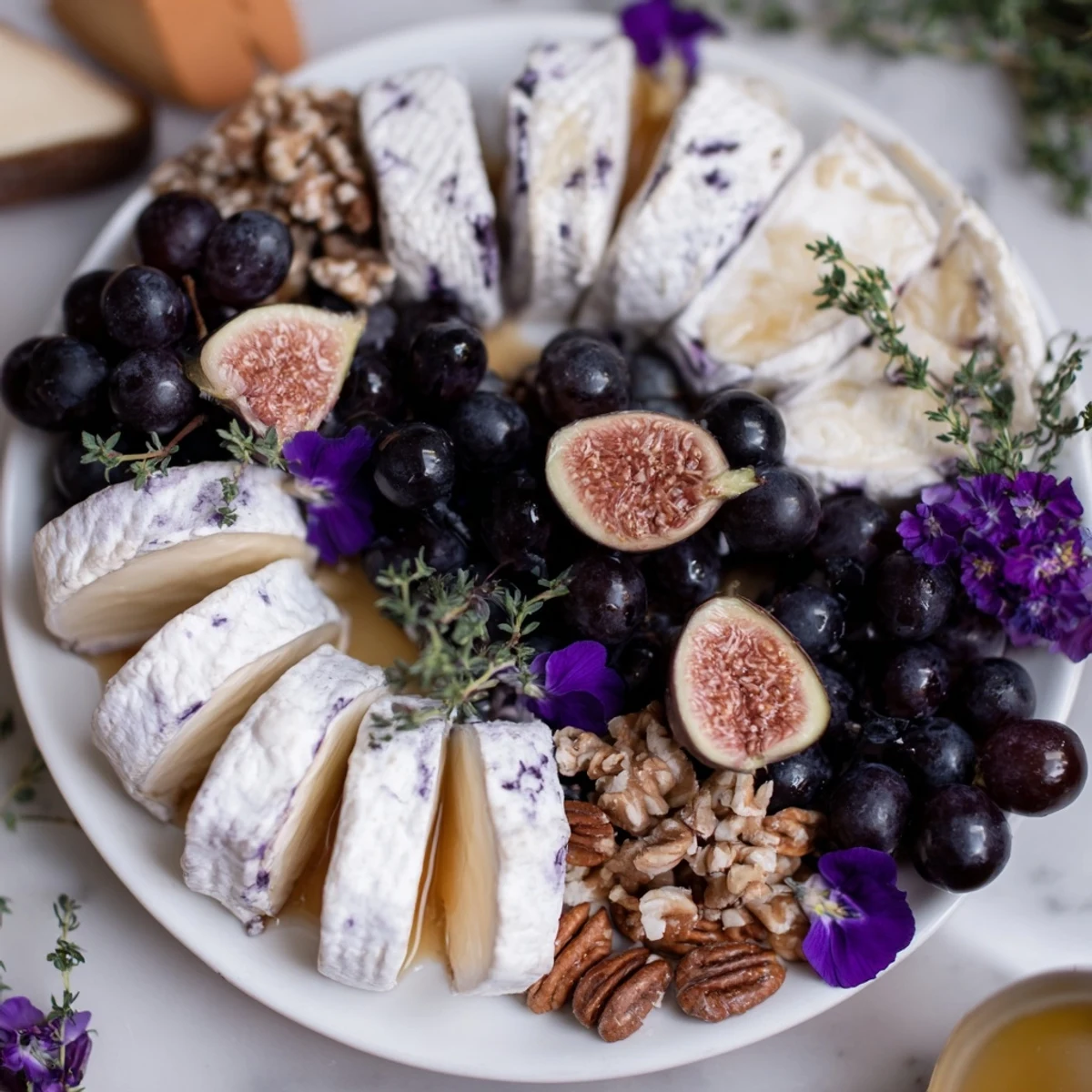 Enjoy the visually stunning Lavender Haze cheese platter, featuring lavender-coated cheese and fresh figs.