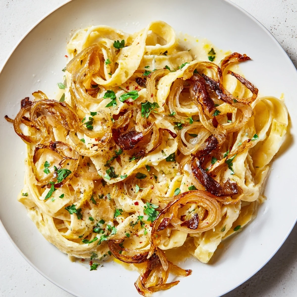 A close-up of steaming One-Pot French Onion Pasta, garnished with fresh parsley, ready to eat.
