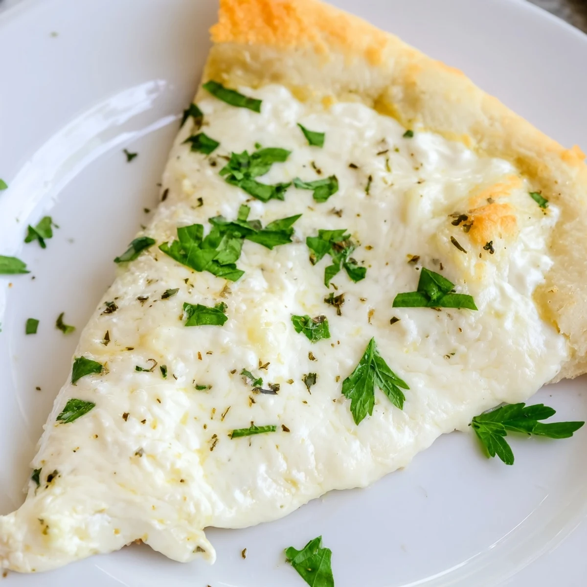 Slice of Creamy Garlic White Pizza on a marble surface, with velvety garlic cream sauce visible and parsley garnish.