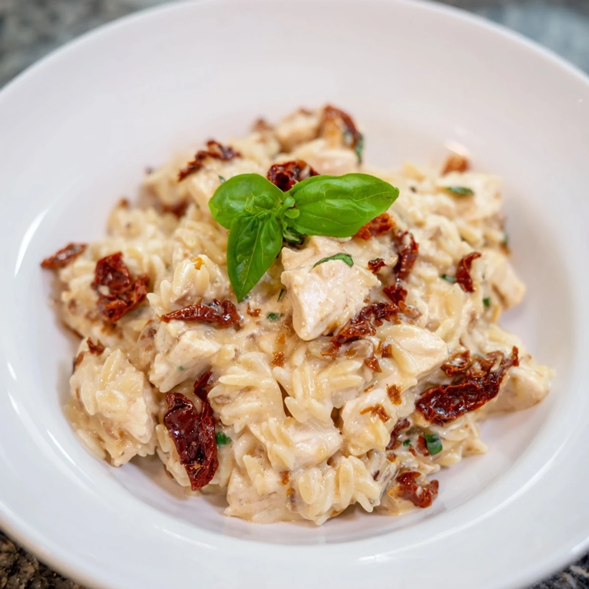 Golden-brown Tuscan Chicken Orzo in a creamy sauce, served hot with fresh basil and melted Parmesan cheese.