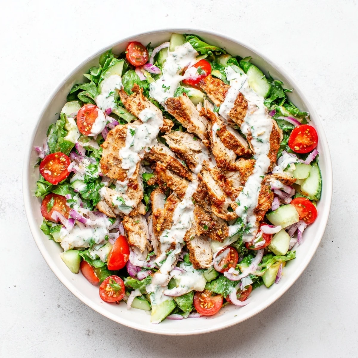 Close-up of Chicken Shawarma Salad Bowl highlighting golden-brown chicken, colorful vegetables, and creamy garlic sauce, ready to be enjoyed by four people.