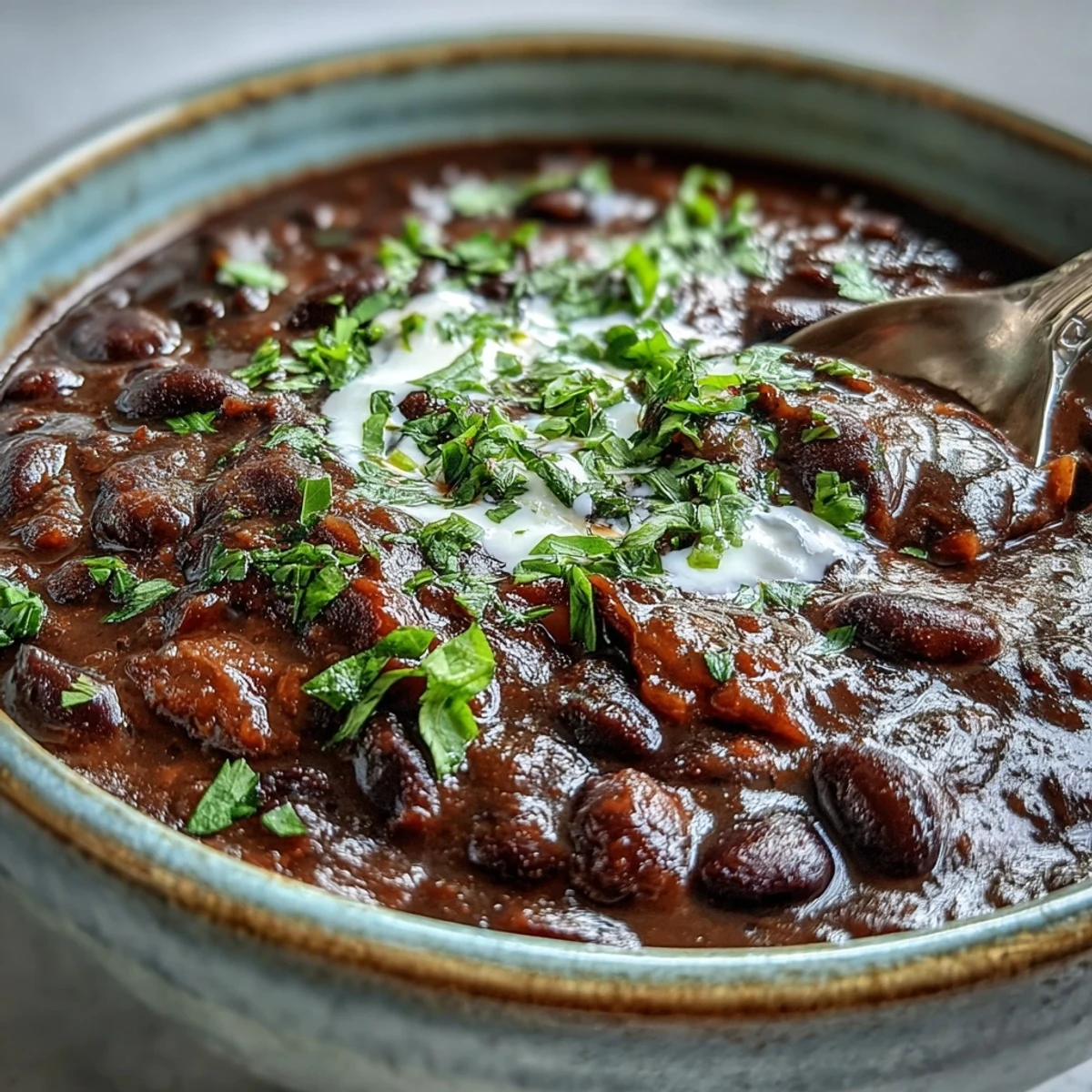 A comforting bowl of black bean soup garnished with sour cream and red onion, ready to enjoy.