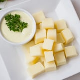 A vibrant close-up shows a cheese platter with Gouda cubes perfect with the tangy mustard dip.