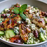 Colorful Mediterranean Pearl Couscous Chicken Bowls showcase diced red bell peppers, cucumbers, cherry tomatoes, and Kalamata olives tossed in a vinaigrette.