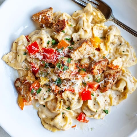A creamy, spicy Zesty Cajun Garlic Parmesan Chicken Tortellini dish garnished for flavor.  