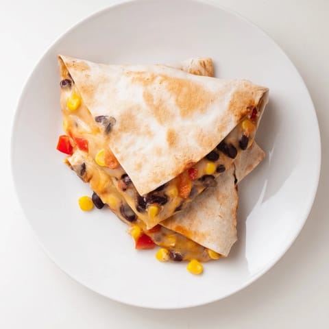 Melted cheese bubbles from a warm tortilla wrap hack filled with seasoned beans.