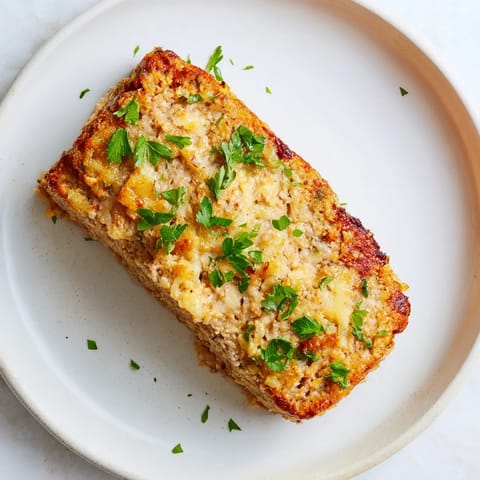 Golden-brown, savory Garlic Parmesan Chicken Meatloaf, a comforting family dinner, freshly baked.