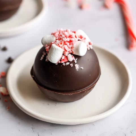 Rich, melty chocolate Hot Cocoa Bomb ready to burst open in a steaming mug of warm milk.