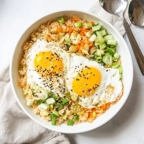 A close-up of kimchi fried rice in a skillet, featuring caramelized kimchi, vibrant green onions, and a glossy finish from sesame oil.