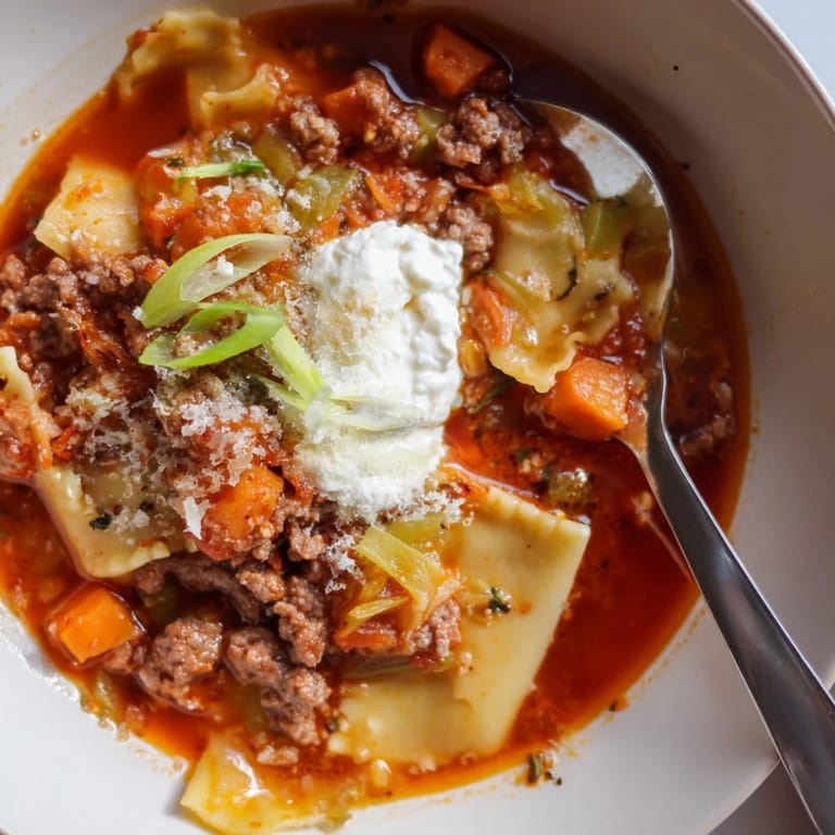 Delicious Lasagne Soup with Kimchi Crunch, garnished with spring onions and herbs.
