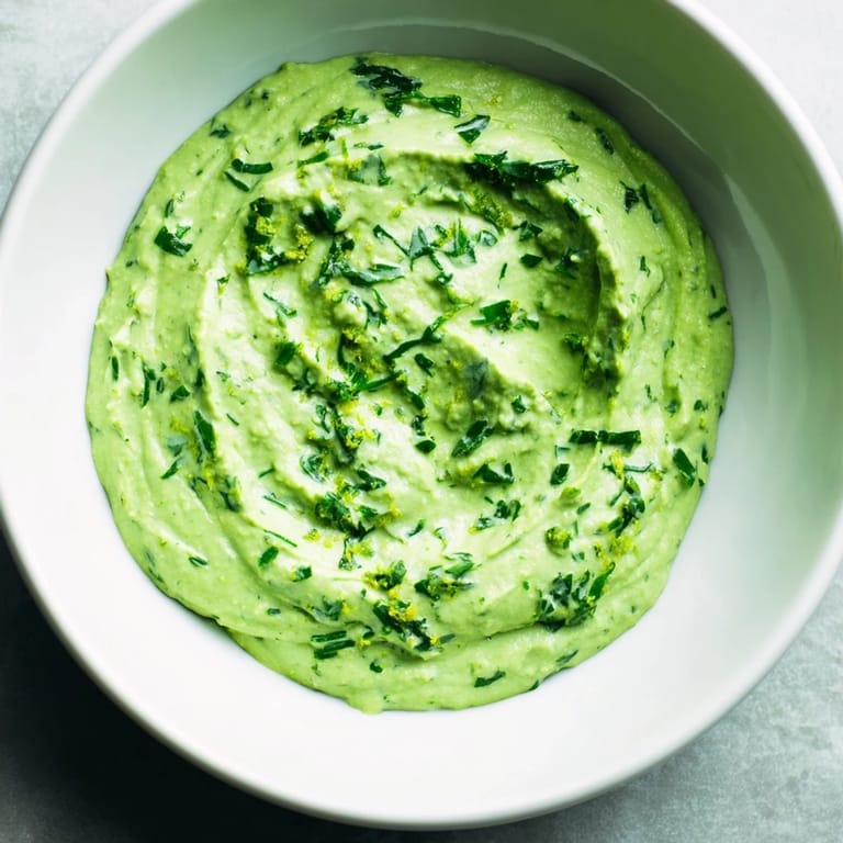 A photo of homemade Green Goddess Dip, swirled and vibrant, perfect for dipping veggies or spreading.