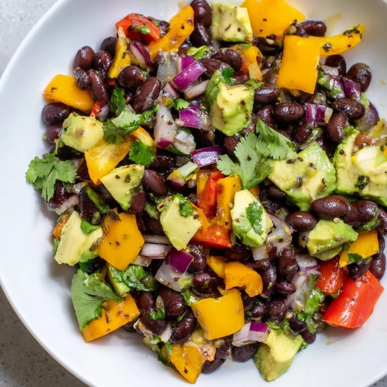 Freshly tossed Southwest Black Bean Salad with avocado, ready to serve as a light and healthy meal.