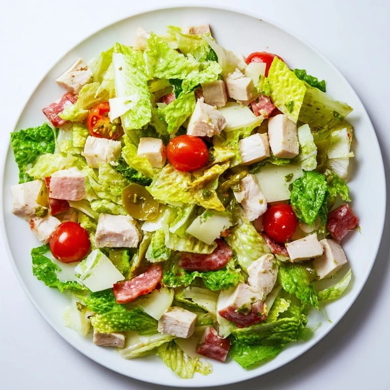 The freshly tossed Italian Deli Chopped Chicken Salad showcases crisp vegetables, savory cured meats, and a bright red wine vinaigrette in a rustic bowl.