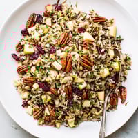 Wild Rice Harvest Salad in a rustic bowl, showcasing glossy cranberries and golden toasted pecans on nutty grains.