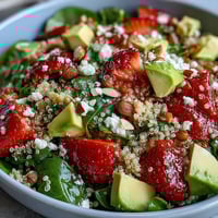 Vibrant strawberry avocado quinoa salad with juicy berries, creamy avocado, and zesty citrus dressing in a white bowl.